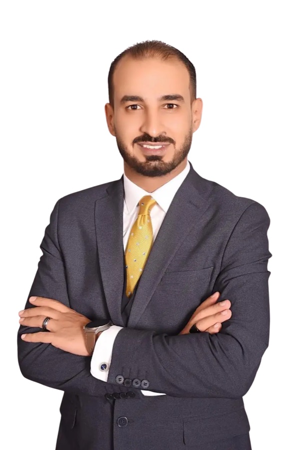 رجل أعمال بلباس رسمي وربطة عنق واقفاً بذراعين متقاطعتين